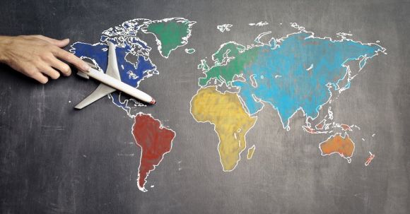 Continent - Top view of crop anonymous person holding toy airplane on colorful world map drawn on chalkboard