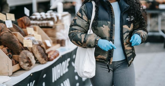 Local Fairs - Black woman in mask walking by street bakery