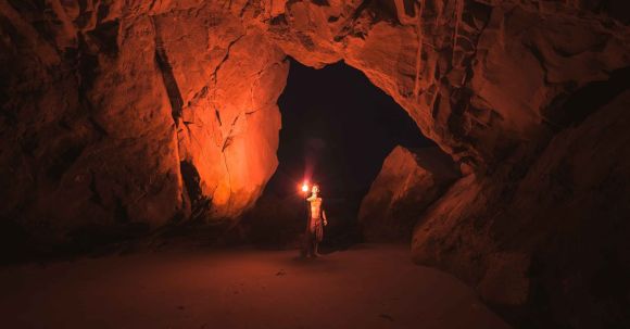 Exploration - Person Standing and Holding Lamp Inside Cave