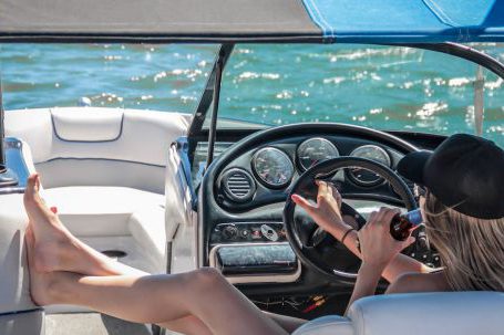 Luxury Travel - Woman Wearing Black Cap Holding Bottle on White Speedboat during Daytime