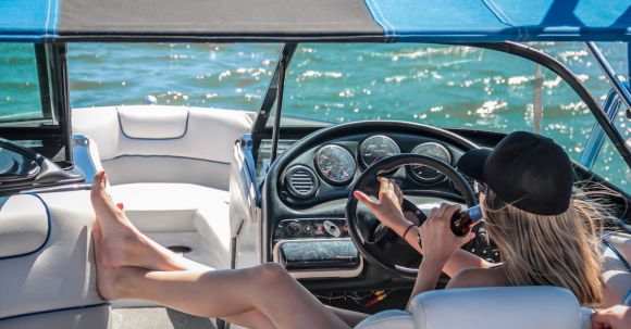 Luxury Travel - Woman Wearing Black Cap Holding Bottle on White Speedboat during Daytime