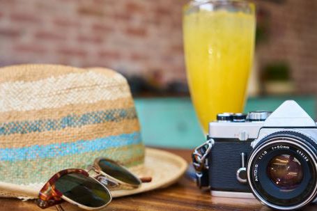Luxury Travel - Gray and Black Dslr Camera Beside Sun Hat and Sunglasses