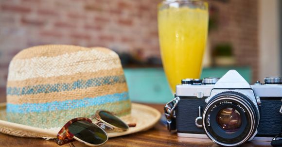 Luxury Travel - Gray and Black Dslr Camera Beside Sun Hat and Sunglasses