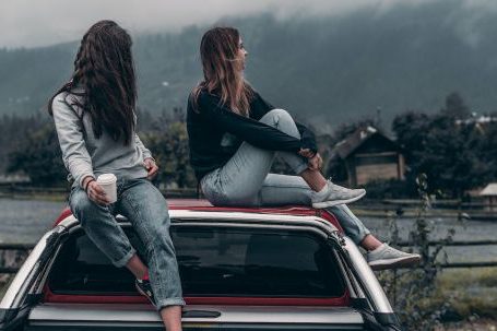 Car Journey - Two Women Sitting on Vehicle Roofs