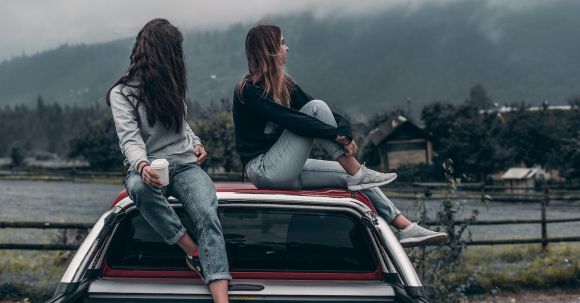 Car Journey - Two Women Sitting on Vehicle Roofs