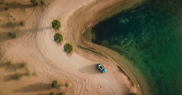 Road Trip - Aerial Photography of Vehicle Parked on Beach Near Bushes
