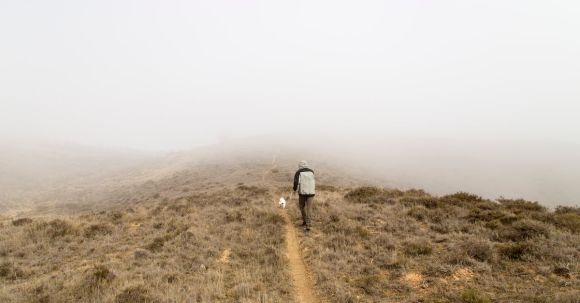 Solo Nature - Man Walking on Top Hill Covered of Fog