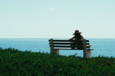 Solo Nature - Woman Sitting on Bench on Grass Shore during Day