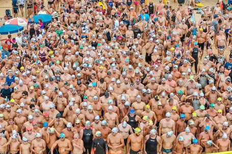 Sporting Event - From above people in swimsuits standing together behind line tape ready to start swim marathon on seashore