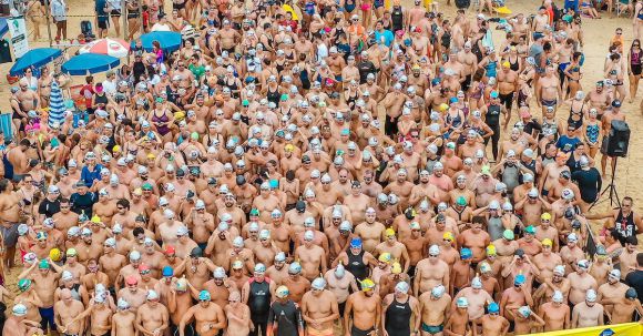 Sporting Event - From above people in swimsuits standing together behind line tape ready to start swim marathon on seashore